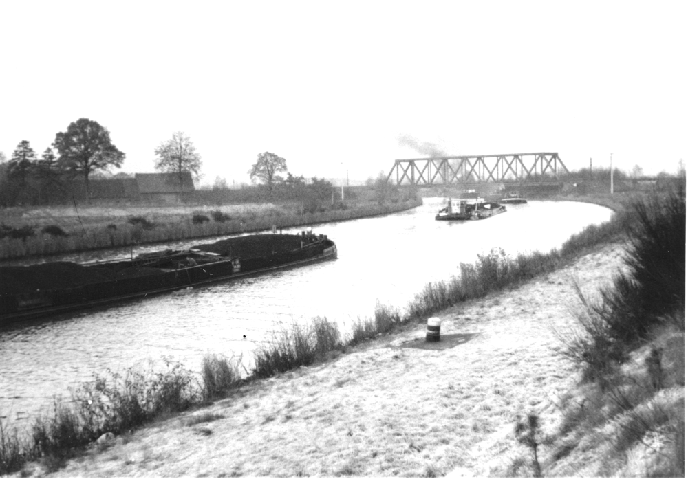 Schleppzug auf der II. Fahrt des Kanals; links Hof Dammann/Hartmann, rechts die alte, für die Kanalverbreiterung im Jahr 2001 ersetzte Eisenbahnbrücke (1956; Foto: Hiltruper Museum)