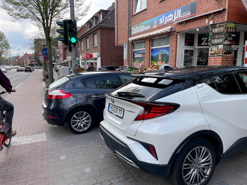 Hiltrup, Marktallee 9: Zwei parkende Autos vor dem arabischen Laden blockieren den Gehweg (9.4.2026, Foto: Henning Klare)