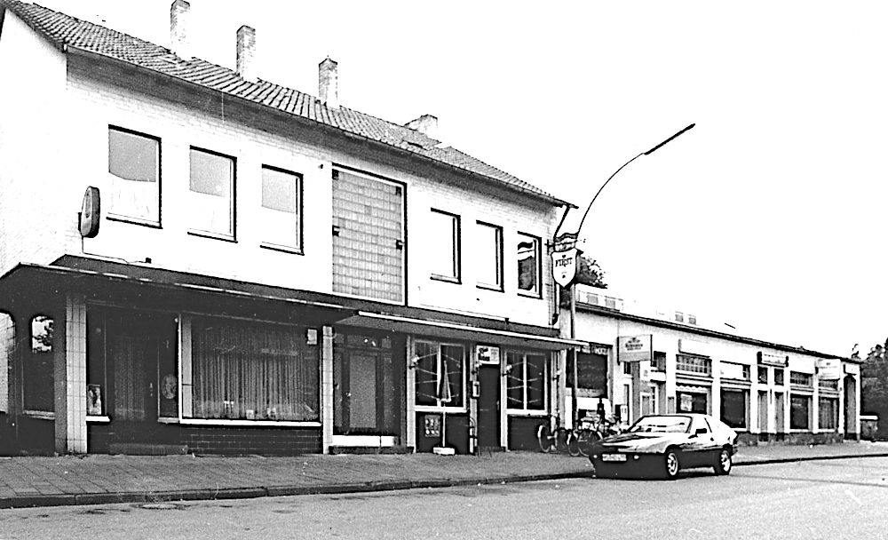 Blick vom Bahnhof nach Westen auf die Kolonnaden, von rechts: Drogerie, Textilgeschäft, Konditor, Kneipe, Frisör (1987, Foto: Hiltruper Museum; Bearbeitung: Henning Klare)