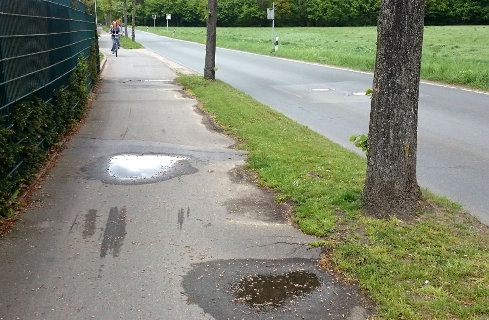 Hiltrup, Hünenburg 73: Baumwurzeln bilden eine Rüttelstrecke für Radfahrer (30.4.2018; Foto: Klare)